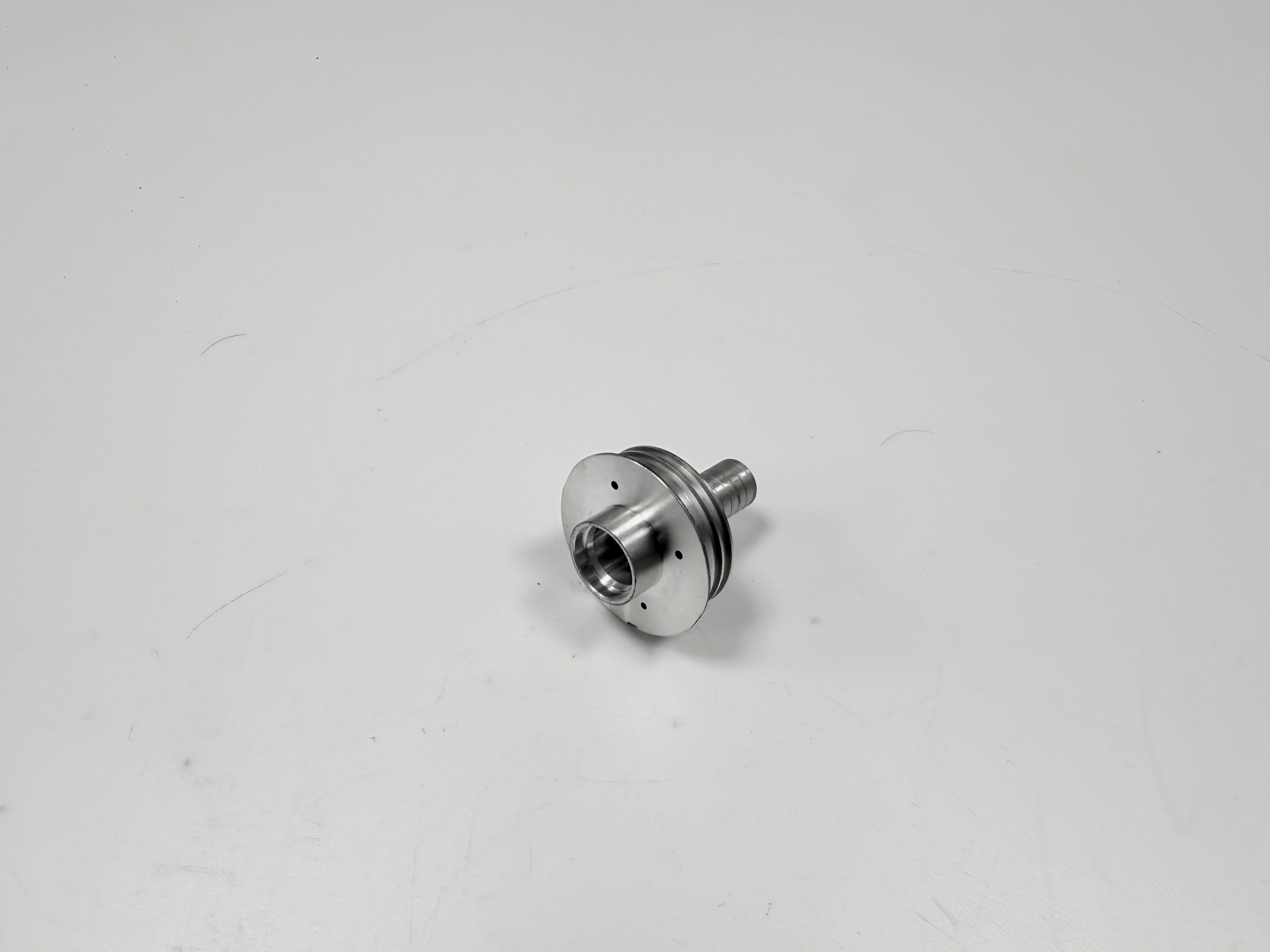 The same turned nozzle shown at an angle to reveal stepped diameters and threaded end features