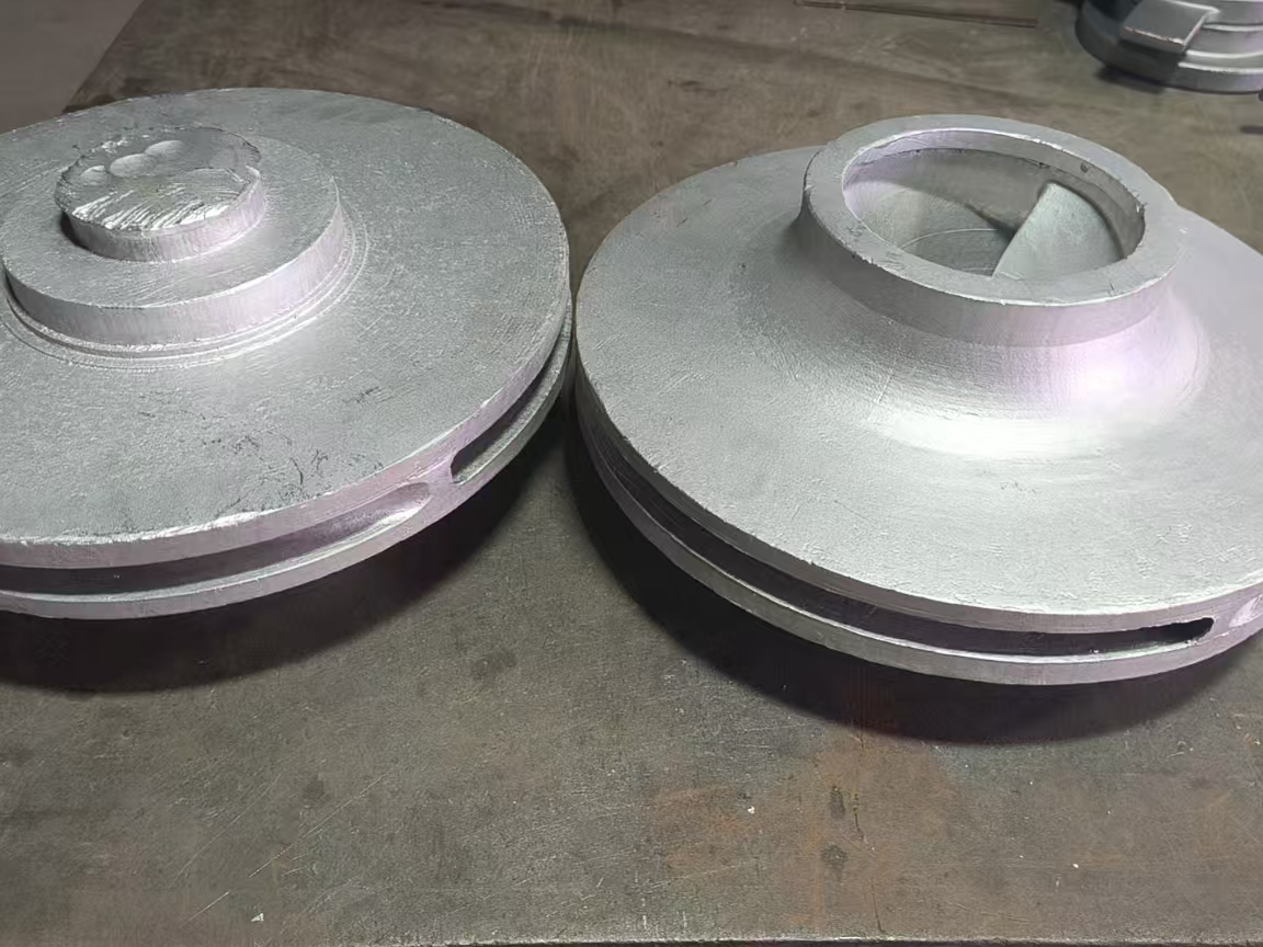 Two unfinished pump impeller bodies with rough casting surfaces